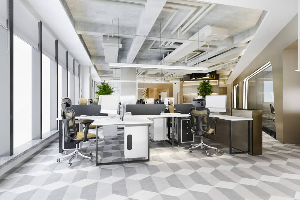 Un bureau moderne à aire ouverte avec des chaises ergonomiques, des écrans d'ordinateur et des plantes en pot - un exemple idéal d'agencement bureaux Île-de-France après un récent projet de rénovation commerces Paris.