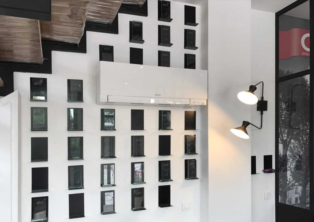 Mur blanc moderne avec des décorations rectangulaires noires, un climatiseur mural et deux lampes murales réglables sous un escalier.