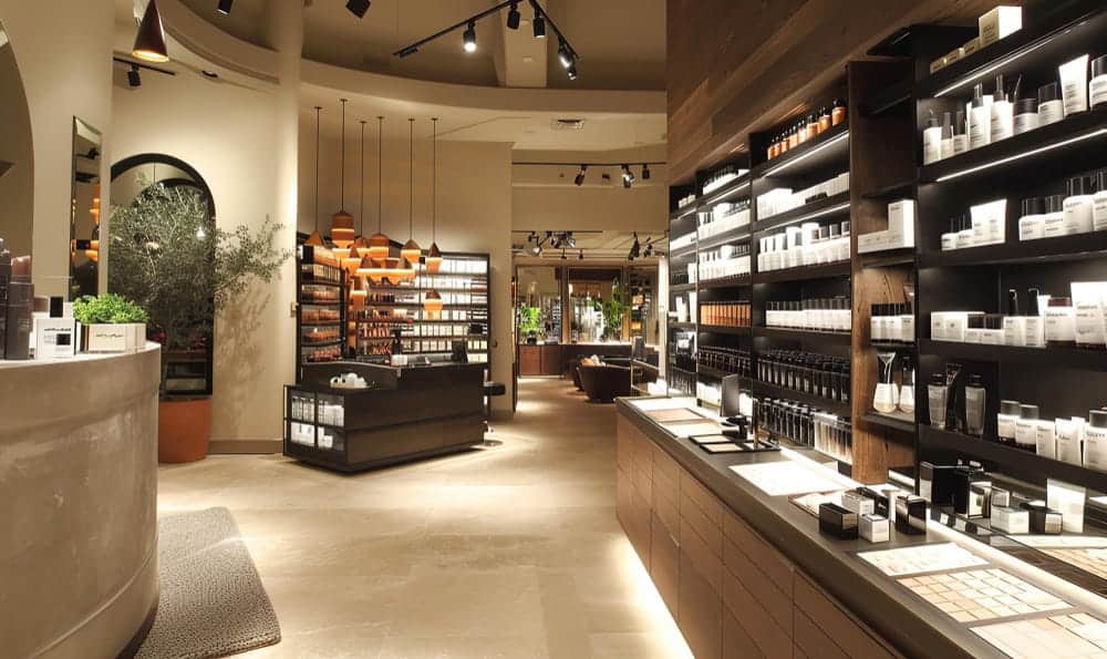 Un magasin de détail bien éclairé avec des étagères remplies de produits cosmétiques, des présentoirs et une plante.