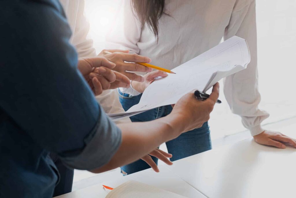 Des personnes collaborant autour d'une table, examinant des documents et des plans.