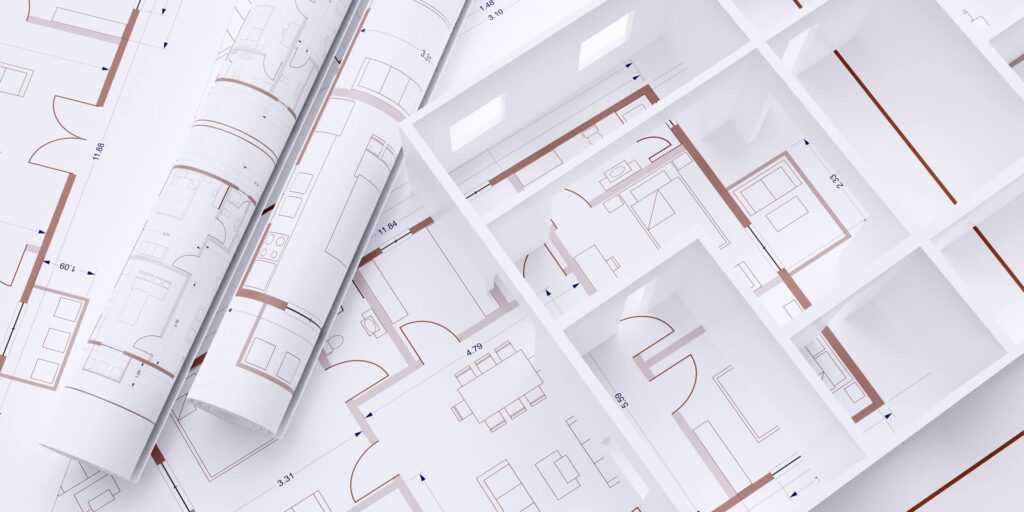 Plans d'étage architecturaux roulés et déroulés sur une surface blanche, montrant la disposition des pièces et du mobilier dans un bâtiment.