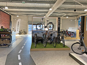Une variété de vélos est exposée dans un magasin, y compris des vélos électriques et des vélos de ville.