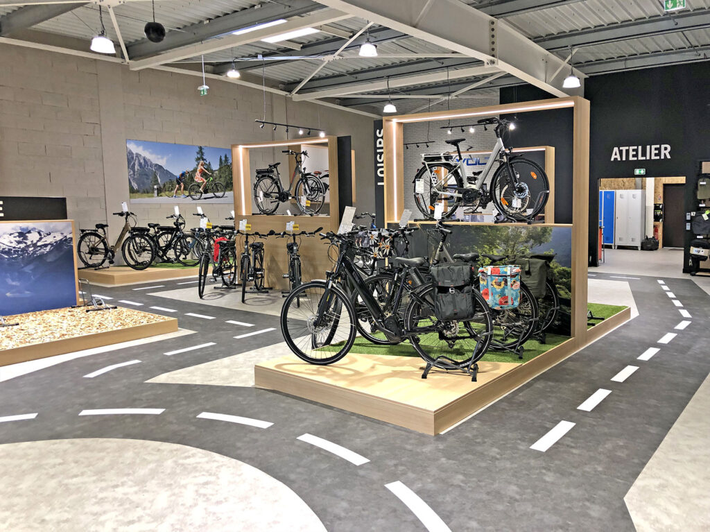 Une exposition intérieure de différents vélos avec un sol sur le thème de la route.