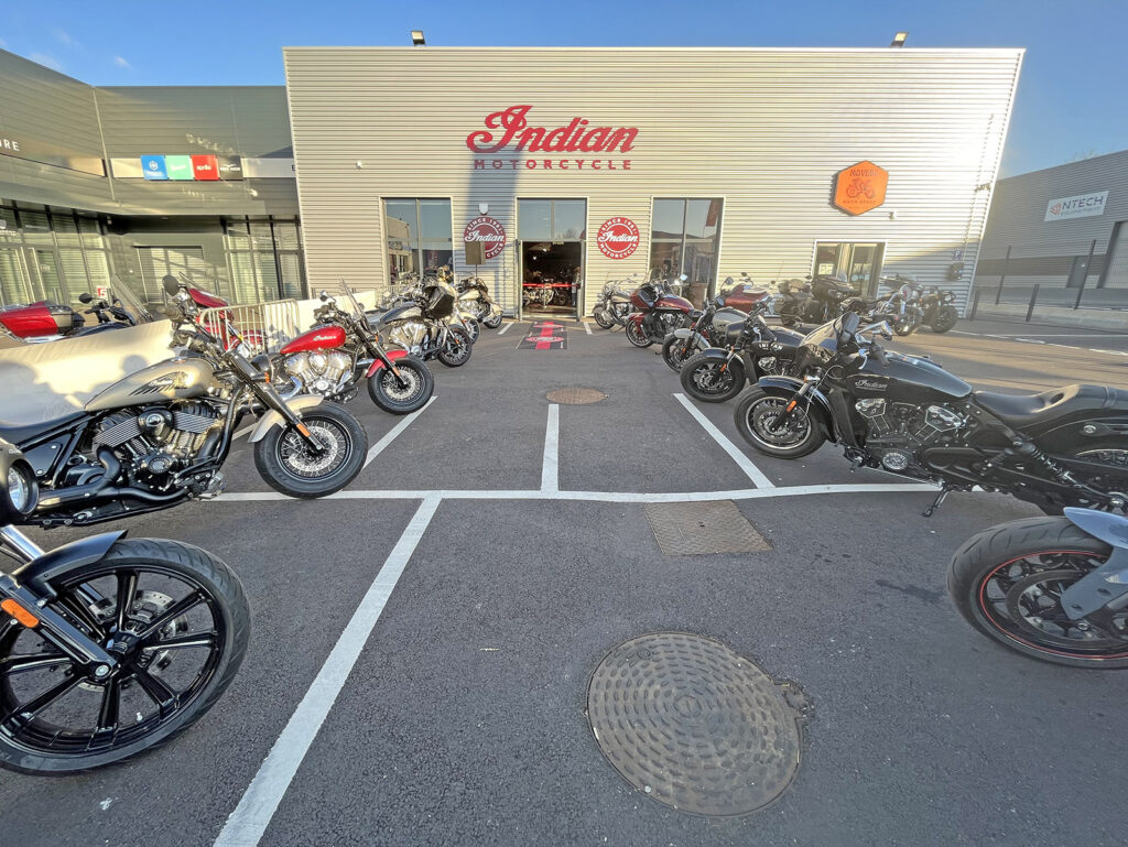 Concessionnaire Indian Motorcycle avec plusieurs motos garées à l'extérieur sous un ciel dégagé.