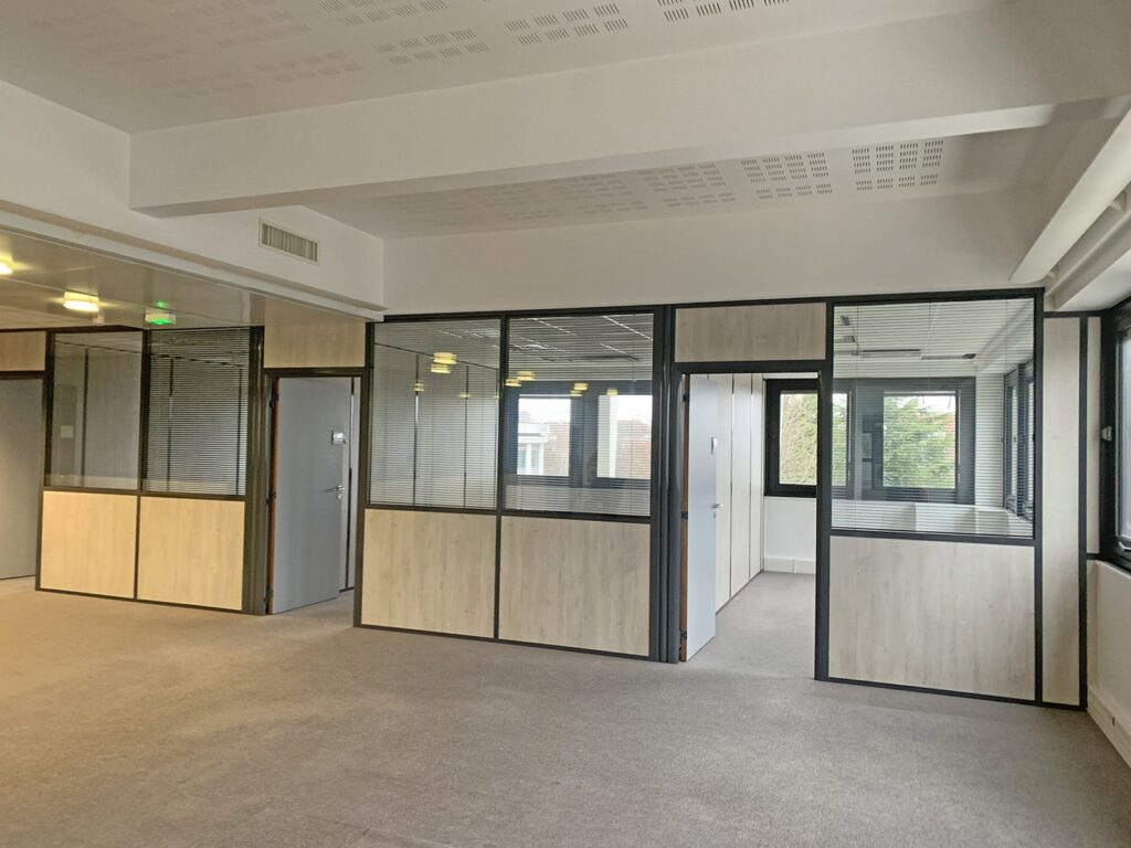 Un bureau vide avec des cloisons en verre et des murs en bois.
