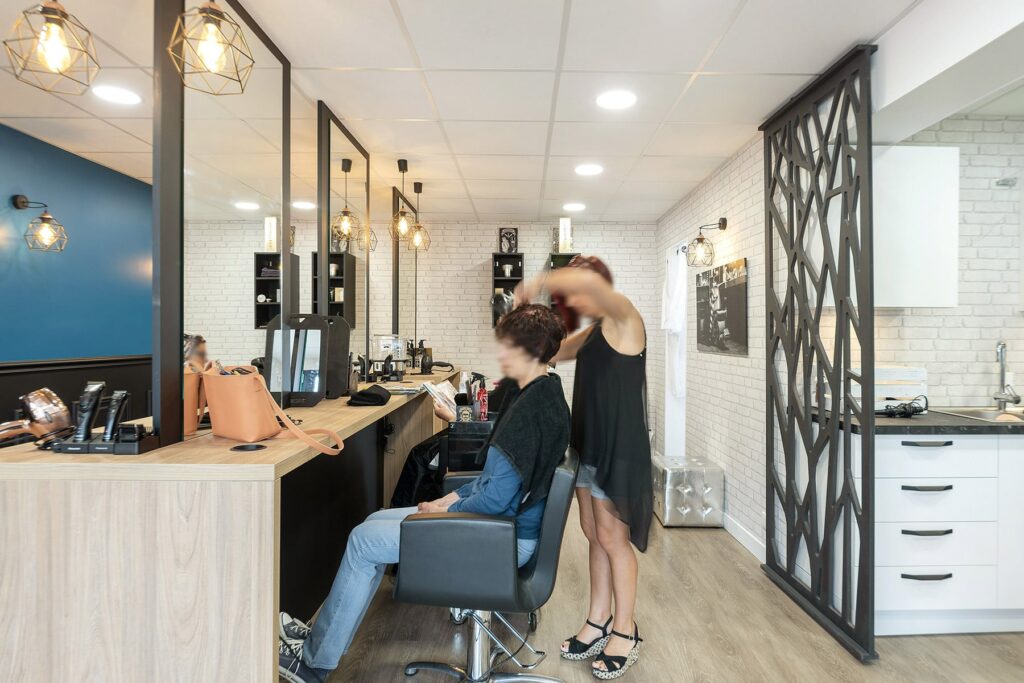 Un coiffeur coiffe les cheveux d'une cliente dans un salon de coiffure.