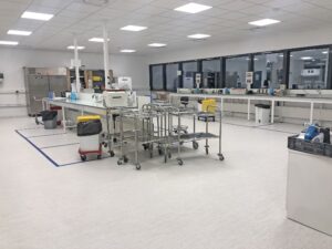 Un laboratoire propre et moderne avec des postes de travail, du matériel de laboratoire et des chariots, doté de grandes fenêtres et d'un éclairage fluorescent.
