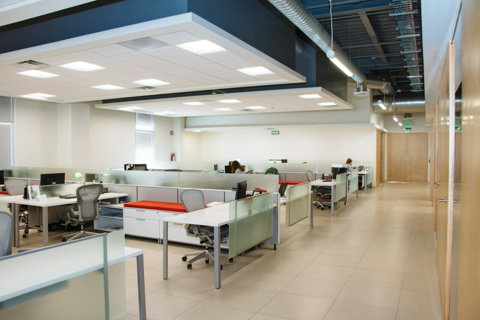 An open plan office with rows of white desks and frosted glass partitions