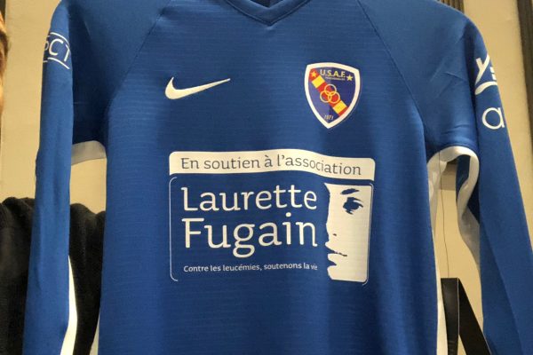 Un maillot de football bleu à manches longues avec l'écusson du club de l'USAF, le logo Nike et le parrainage de l'association de lutte contre la leucémie "Laurette Fugain" sur le devant.
