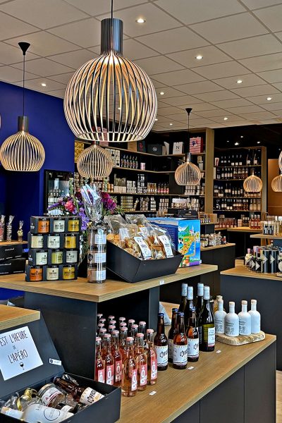 Intérieur d'un magasin de produits gastronomiques avec des étagères remplies de vin, de bocaux et de coffrets cadeaux.