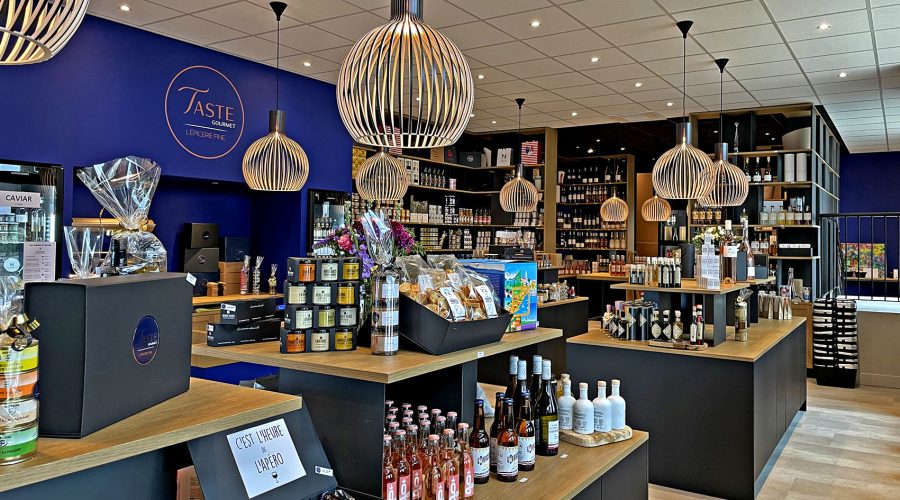 Intérieur d'un magasin de produits gastronomiques avec des étagères remplies de vin, de bocaux et de coffrets cadeaux.